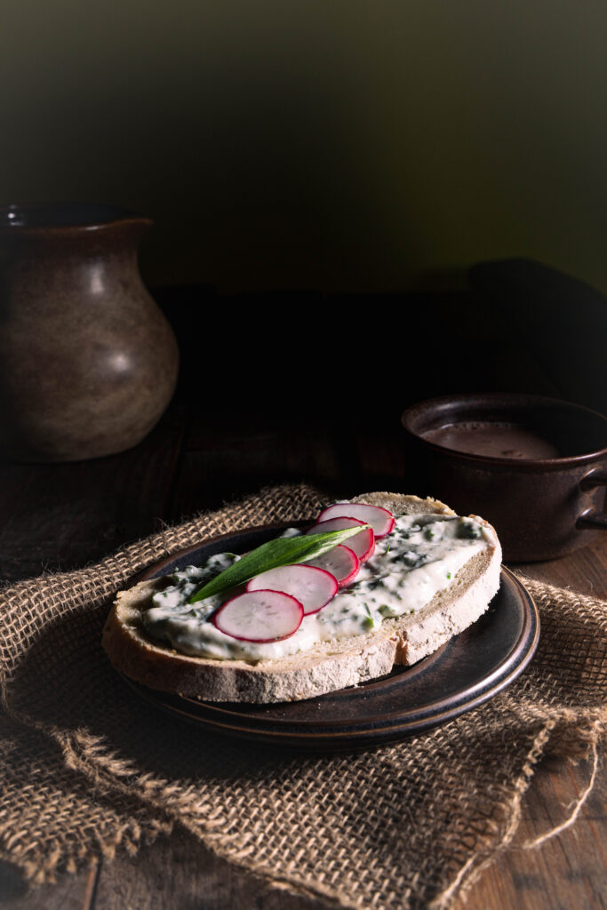 Bärlauch-Vrischkäse auf einer Scheibe Brot, mit Radieschen.