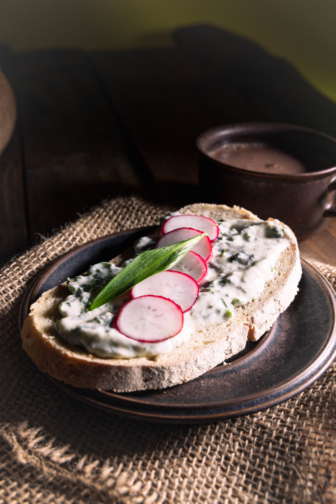 Bärlauch-Vrischkäse auf einer Scheibe Brot, mit Radieschen.