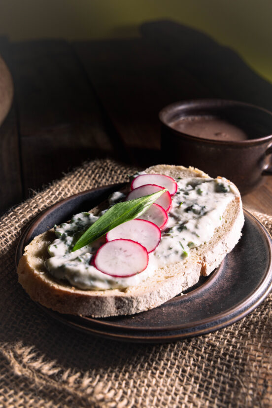 Bärlauch-Vrischkäse auf einer Scheibe Brot, mit Radieschen.