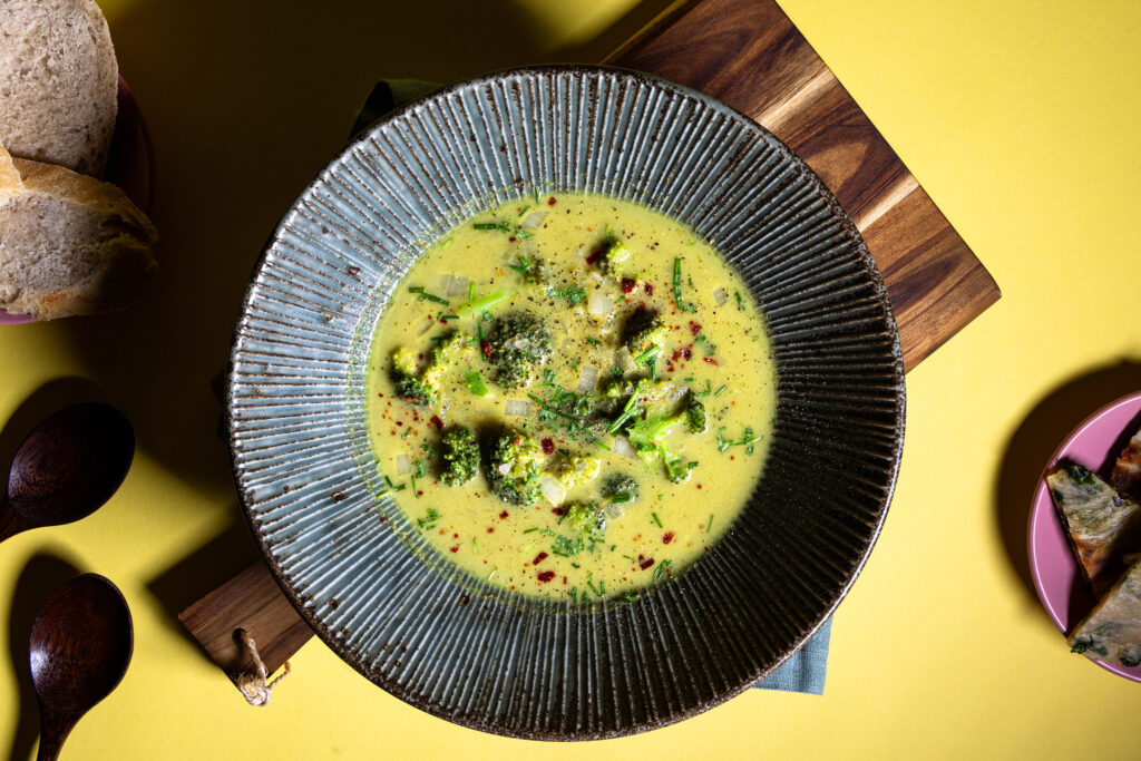 Brokkoli Curry Cremesuppe in einer Schale, dazu Brot als Beilagen