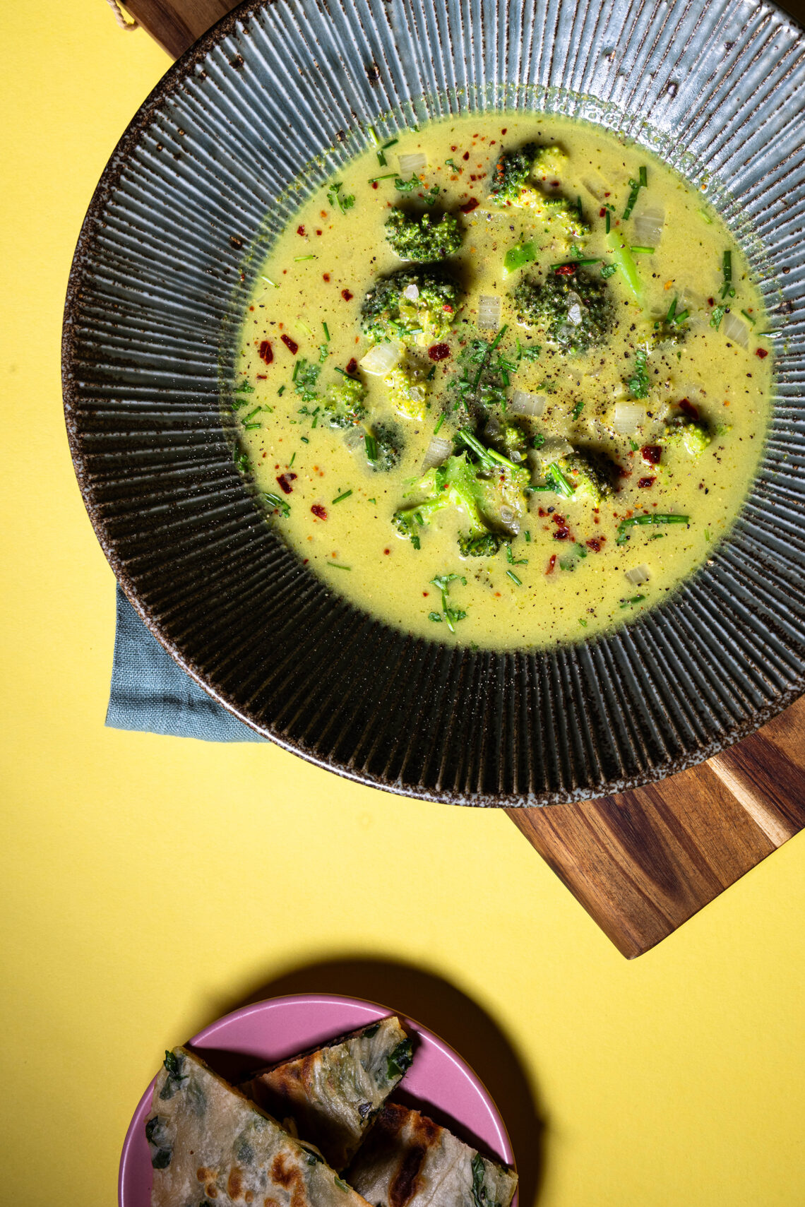 Vegane Brokkoli-Curry-Cremesuppe in einer Schale, mit Beilage