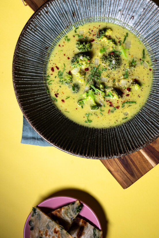 Vegane Brokkoli-Curry-Cremesuppe in einer Schale, mit Beilage
