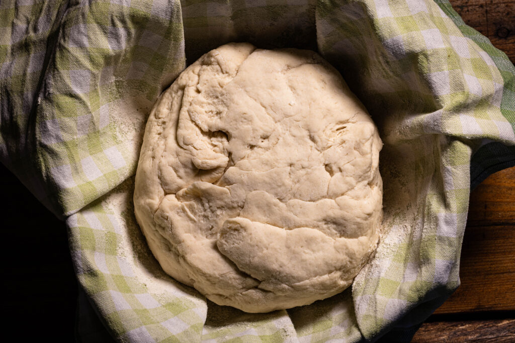 Ein Brotteig in einer Schale mit einem bemehlten Tuch.