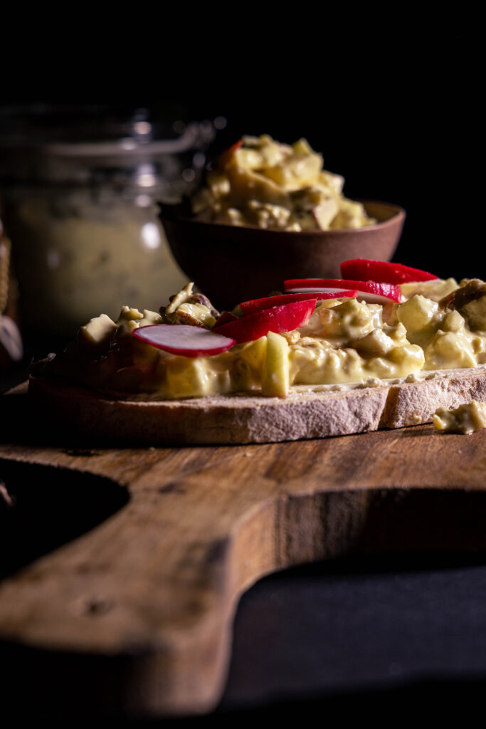Curry-GeVlügelsalat mit selbstgemachtem Hühnchenfleisch aus Seitan, in einer Schale und auf Brot.