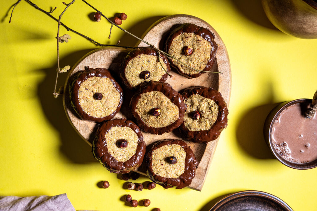 Haselkätzchenplätzchen - Nusskekse mit Haselkätzchenmehl auf einem herzförmigen Holzteller