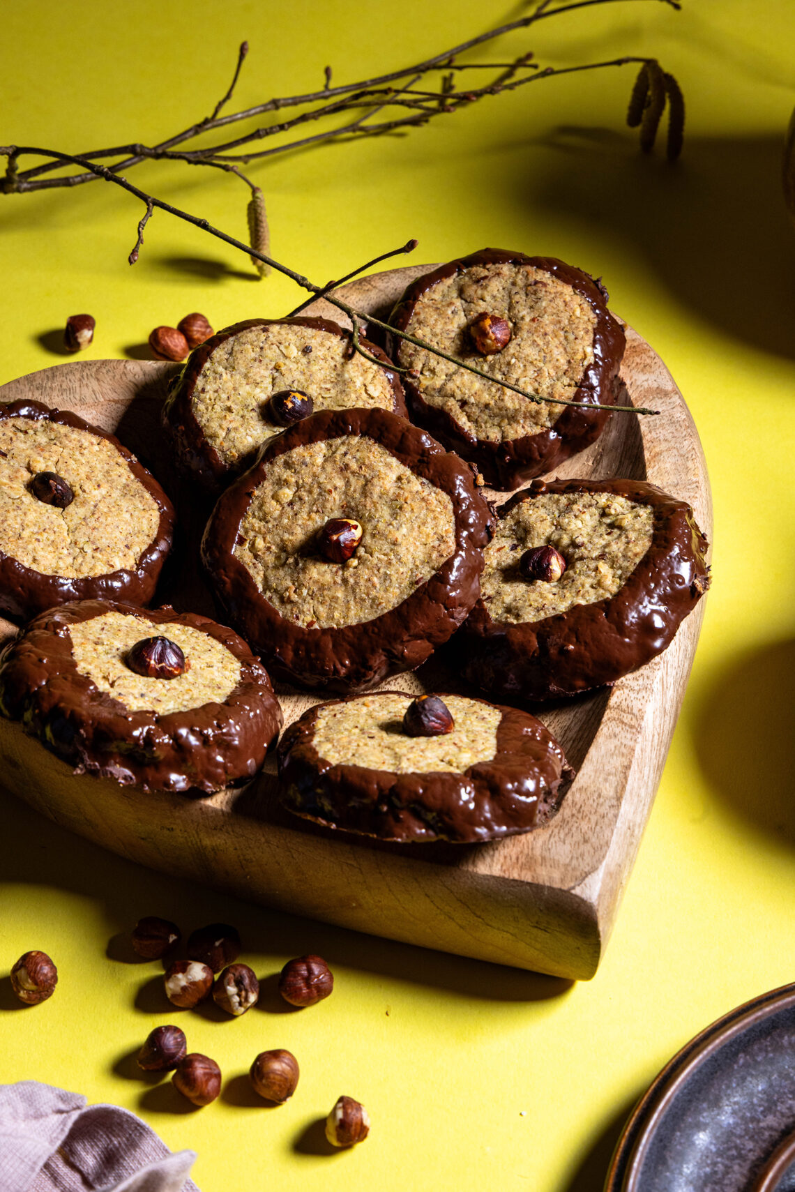 Haselkätzchenplätzchen - Nusskekse mit Haselkätzchenmehl auf einem herzförmigen Holzteller