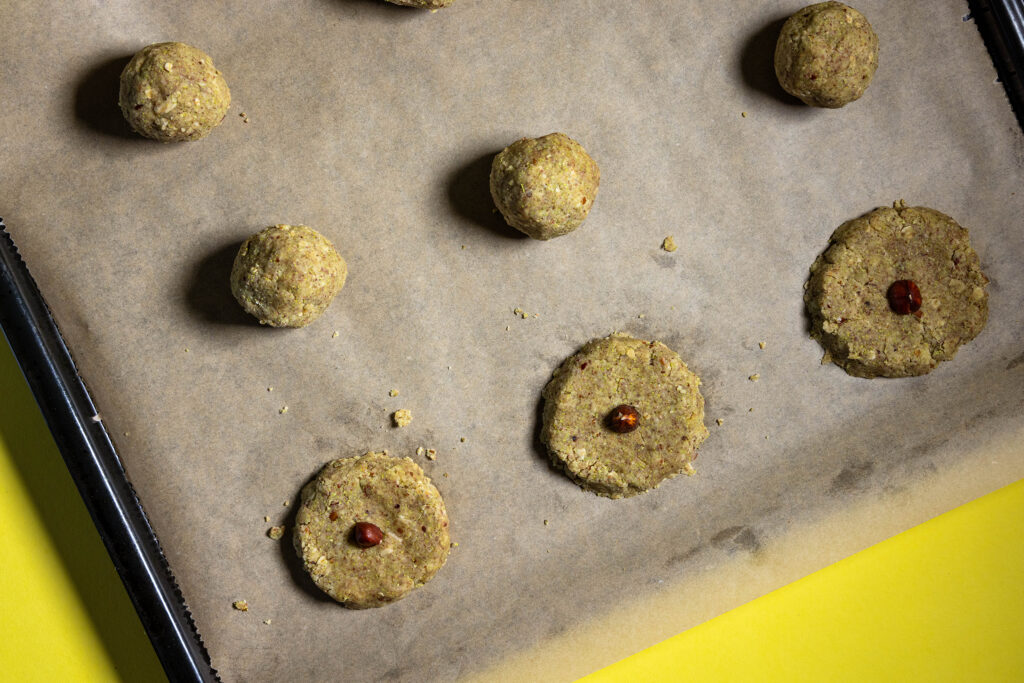 Haselkätzchenplätzchen werden auf einem Backblech mit Backpapier geformt.
