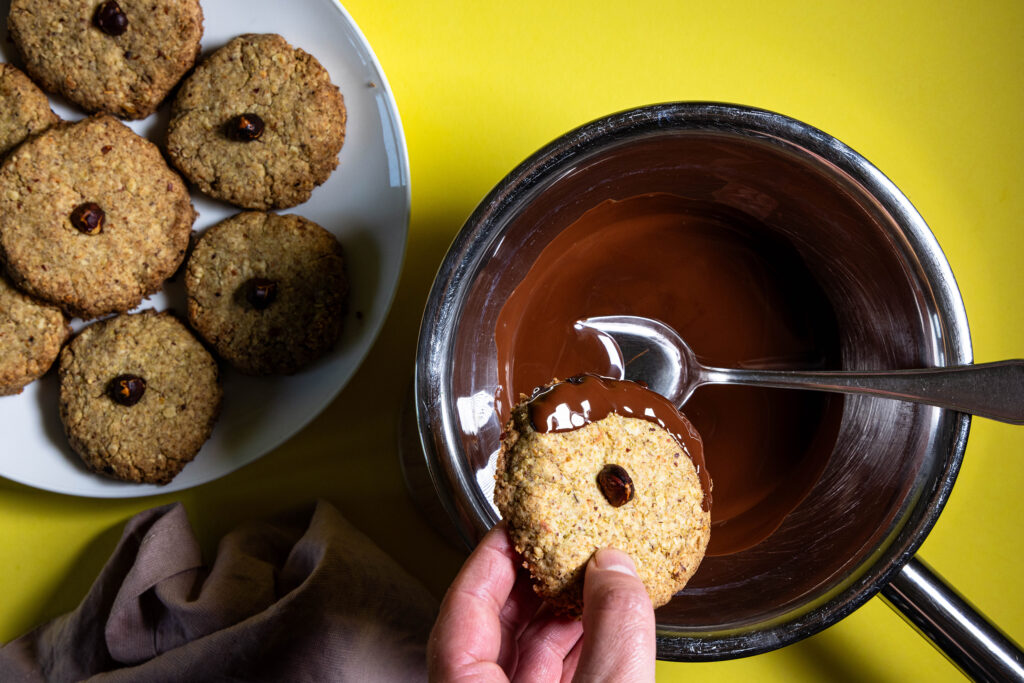 Haselkätzchenplätzchen werden mit geschmolzener Schokolade verziert.