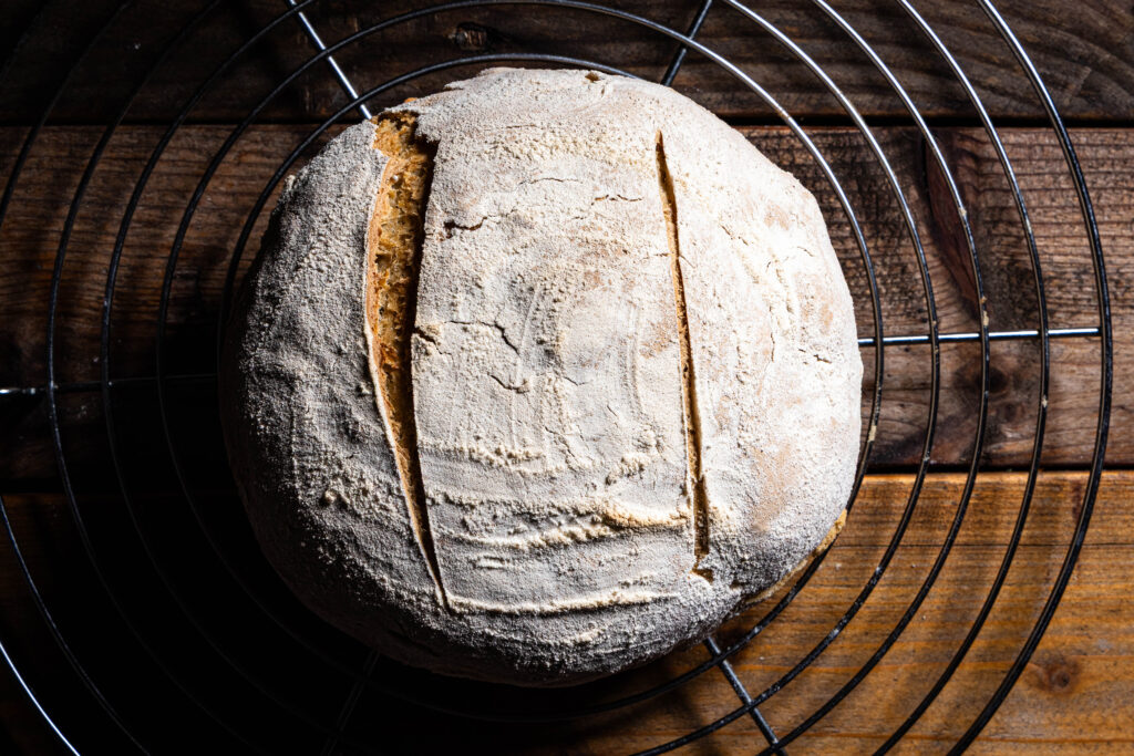 Ein frisch gebackenes Kefir-Roggenbrot kühlt auf einem Rost aus.