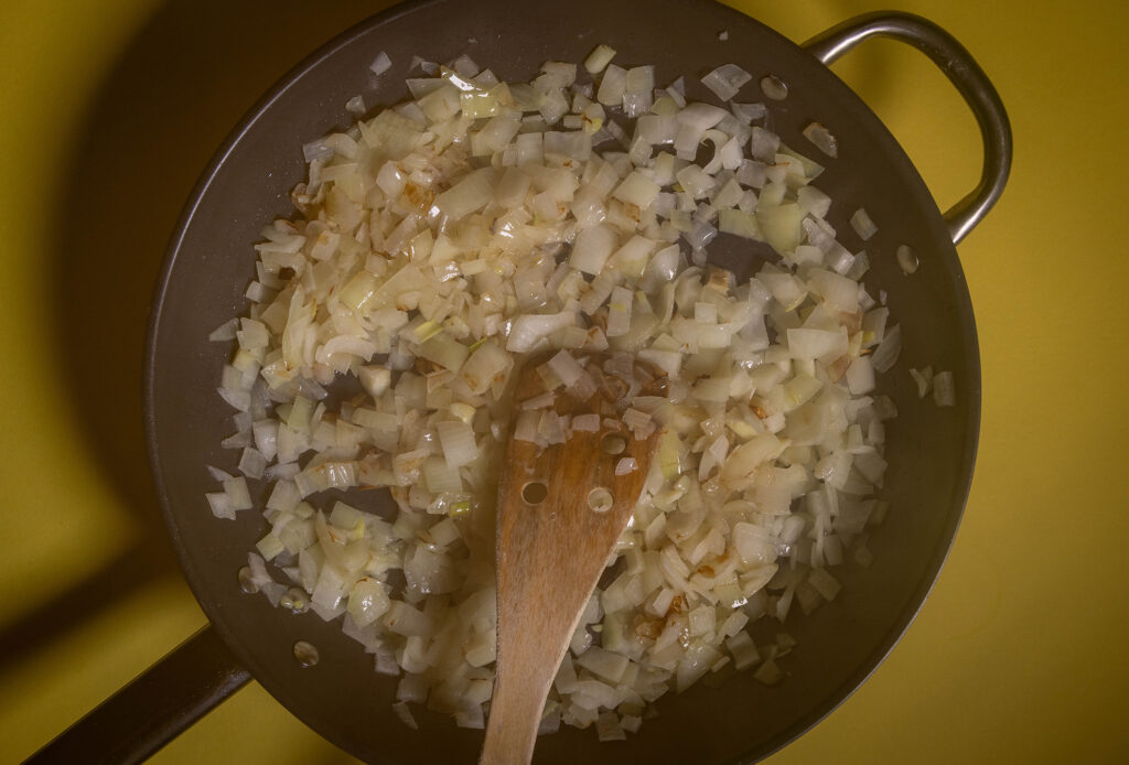Zwieblwürfel braten in einer Pfanne.