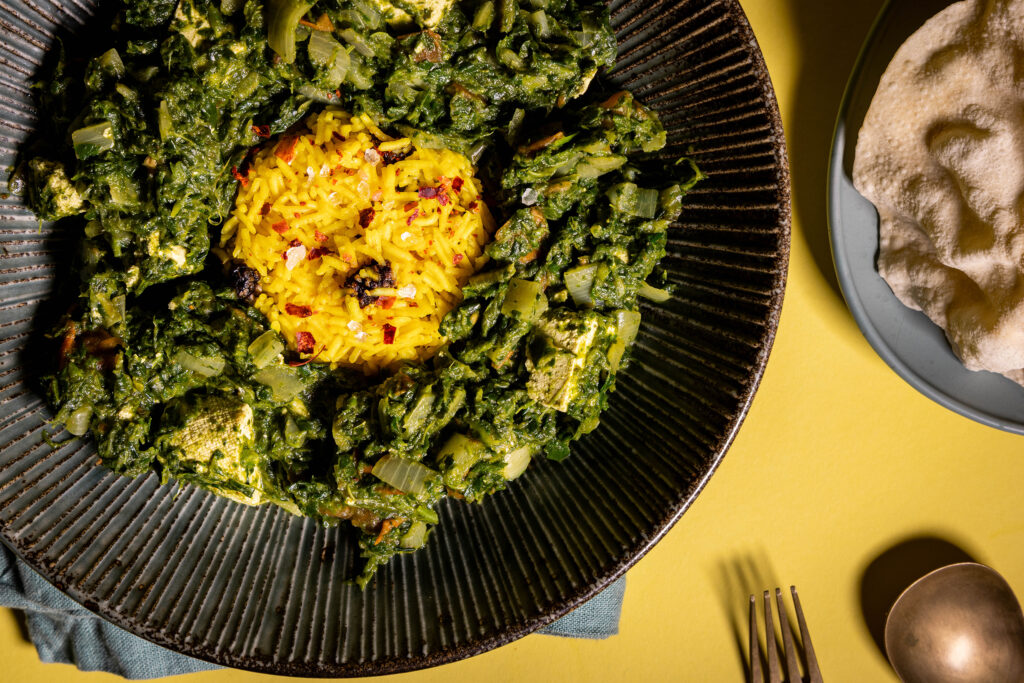 Palak Paneer – mit veganem, selbstgemachtem, indischen Paneer-Käse - in einer Bowl, dazu Papadam