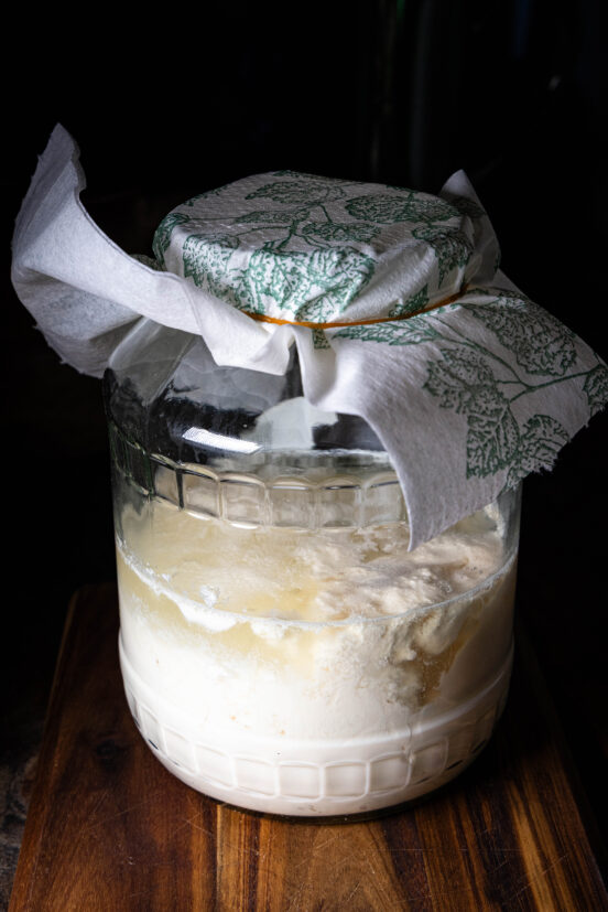 Sojakefir – veganer Kefir fermentiert in einem abgedeckten Glas.