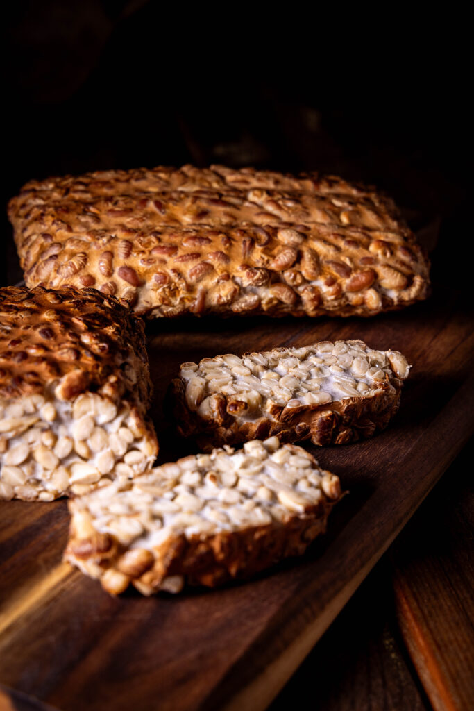 Geräucherter Tempeh angeschnitten auf einem Holzbrett