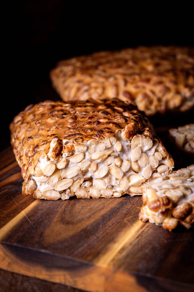 Geräucherter Tempeh - selbstgemacht - angeschnitten auf einem Holzbrett