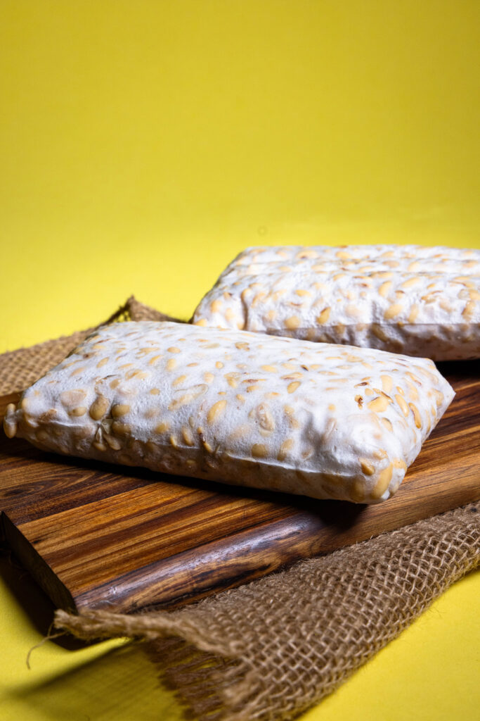 Selbstgemachter Tempeh, zwei frische Blöcke auf einem Holzbrett