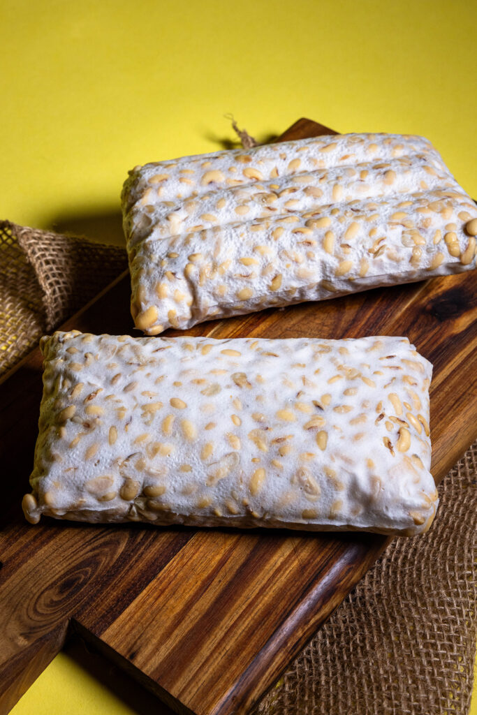 Selbstgemachter Tempeh, zwei frische Blöcke auf einem Holzbrett.