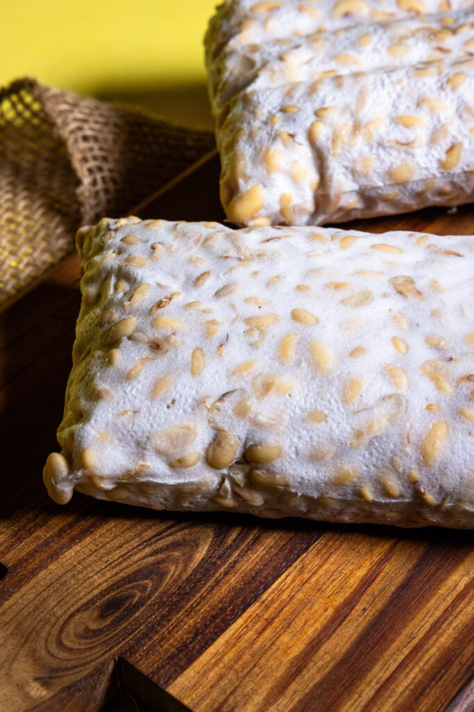Selbstgemachter Tempeh, zwei frische Blöcke auf einem Holzbrett.
