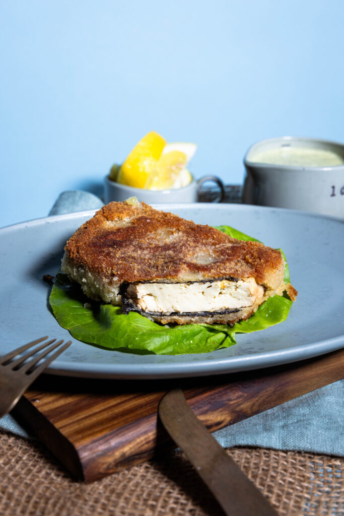 Tofu-BackVisch in knuspriger Panade, angeschnitten auf einem Teller.