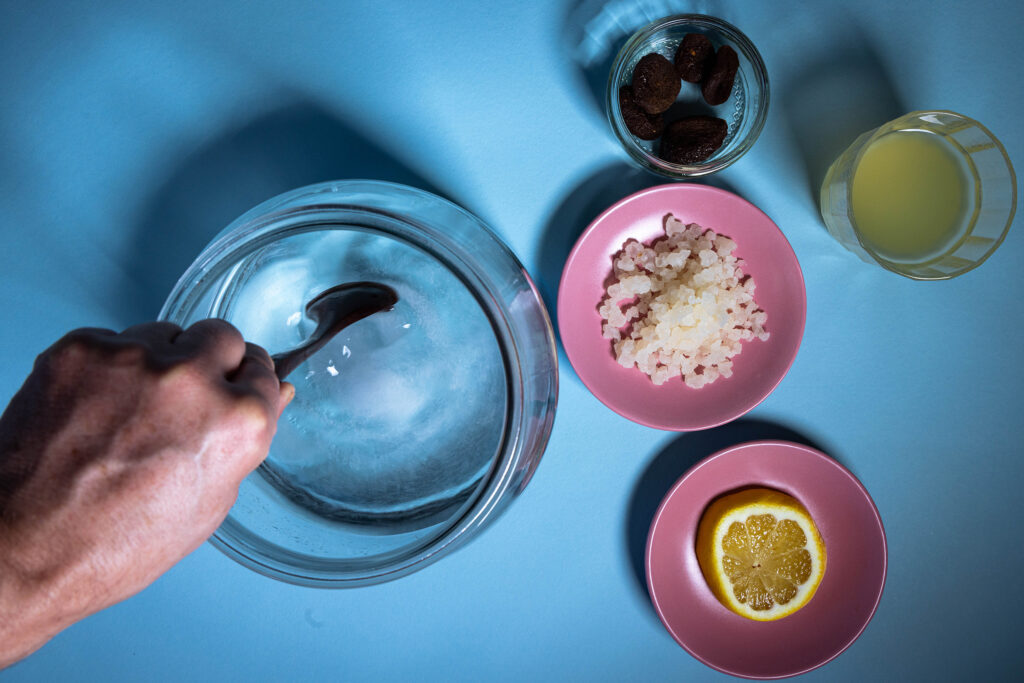 Zucker wird in einem Galsgefäß in Wasser verrührt.