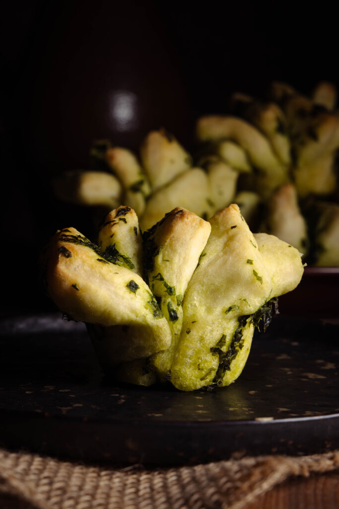 Ein Bärlauch-Zupfbrot auf einem Teller, mehrere dahinter