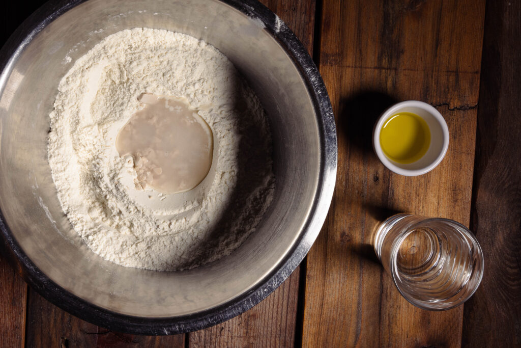 Hefe mit Zucker und Wasser in einer Mehlmulde.