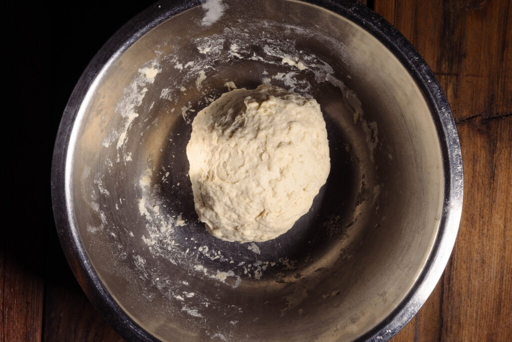 Ein frisch gekneterer Hefeteig in einer Metallschüssel.