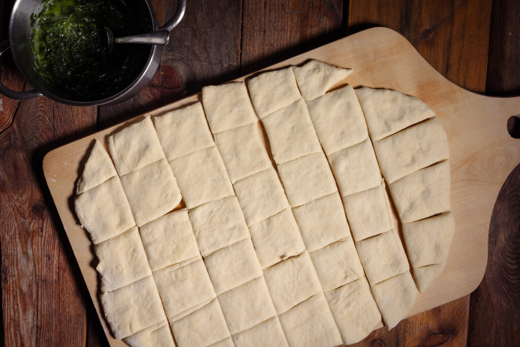 Ein ausgerollter Hefeteig, in Rechtecke geschnitten.