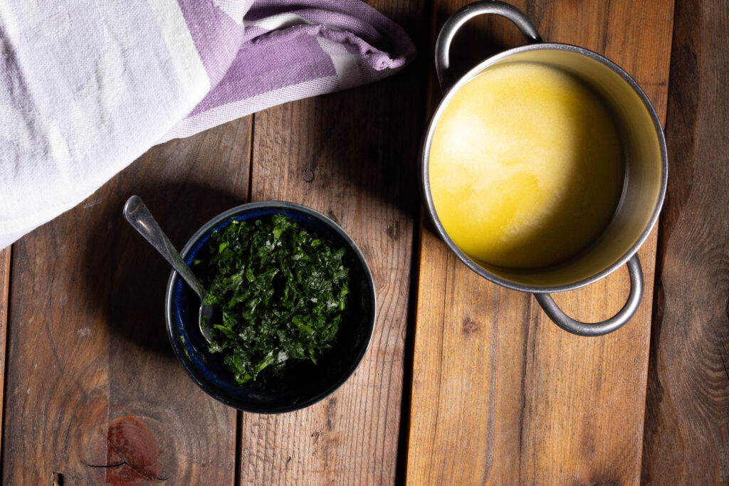 Geschmolzene, vegane Butter in einem Topf, fein gehackter Bärlauch in einer Schale.