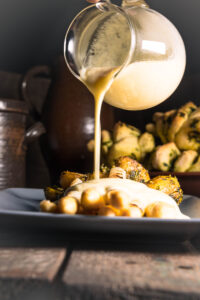 Vegane Sauce Hollandaise wird auf gegrillten Spargel gegeben.