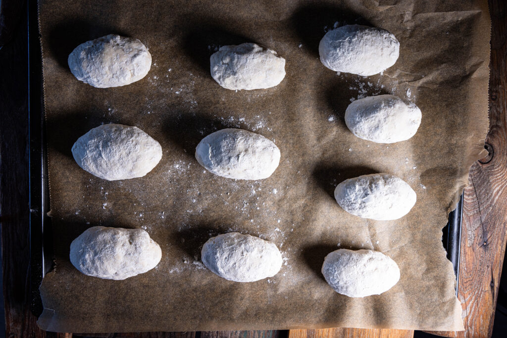 10 Dinkelbrötchen-Rohlingen auf einem Backblech.