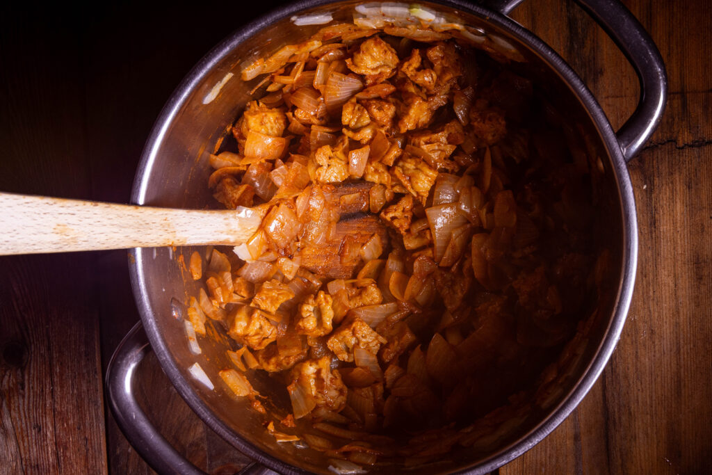 Zwiebeln, Seitan und Gewürze braten in einem großen Topf.