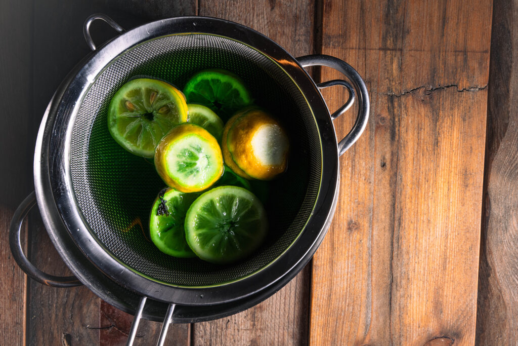 Waldmeistersirup wird in einem Topf abgesiebt..