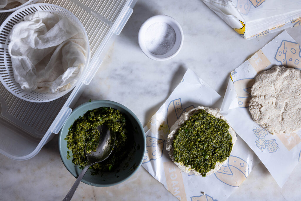 Pesto wird auf einer Hälfte der aufgeschnittenen, rohen Camembertlaibe verteilen.