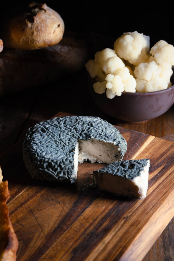 Blumenblau – Veganer Blauschimmelkäse auf Blumenkohlbasis - angeschnitten auf einem Holzbrett