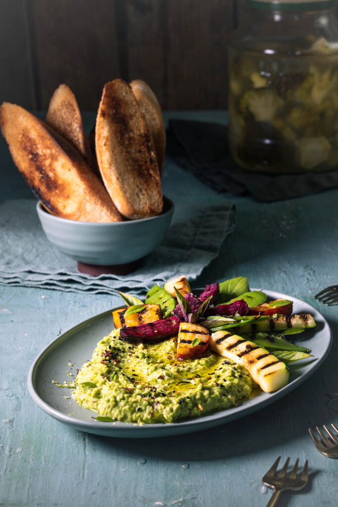 Grüner Umami-Dip mit Beilagen auf einem Tisch.