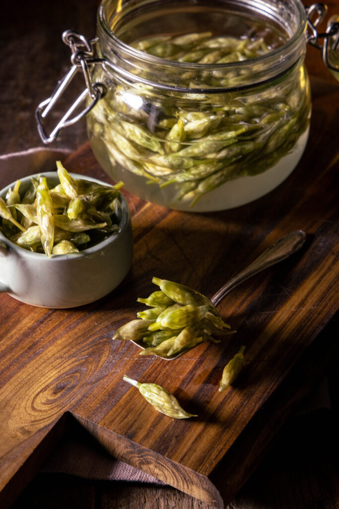 Fermentierte Bärlauchknospen im Glas, in einer Schale und auf einem Löffel.