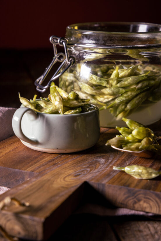 Fermentierte Bärlauchknospen im Glas, in einer Schale und auf einem Löffel.