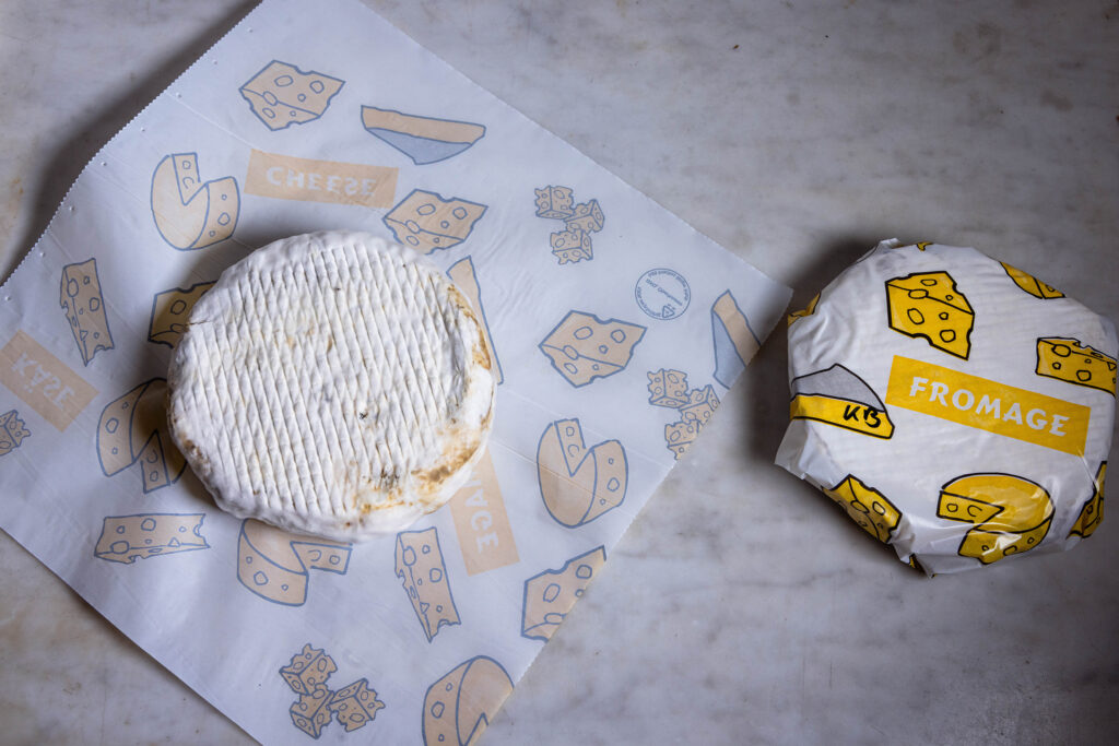 Vegane Briekäse mit Lauchasche werden in Käsepapier verpackt.