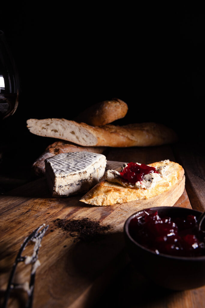 Kohlibrie - veganer Weißschimmelkäse mit Lauchasche - auf einem Stück Brot mit Preiselbeermarmelade