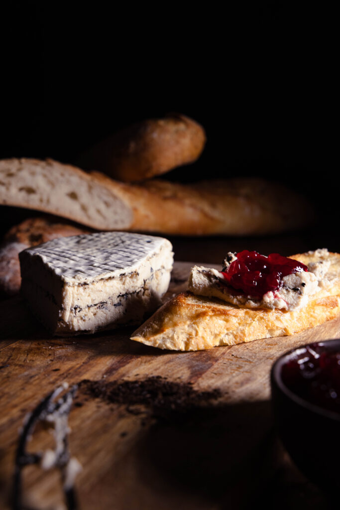 Kohlibrie - veganer Weißschimmelkäse mit Lauchasche - auf einem Stück Brot mit Preiselbeermarmelade
